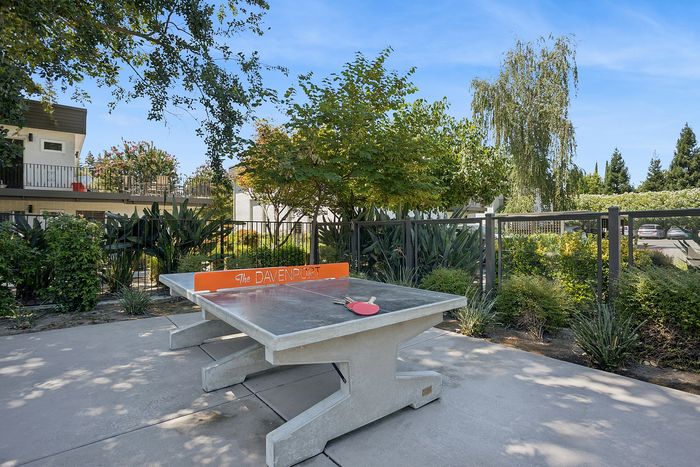 Inviting outdoor area with a stylish ping pong table surrounded by lush greenery at The Davenport apartments.