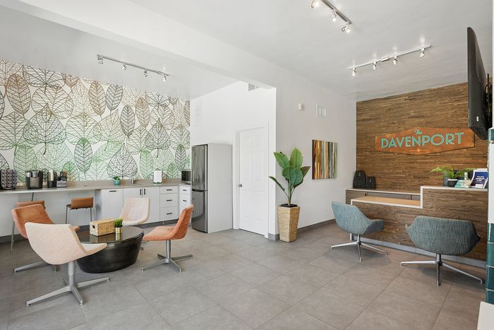 Modern lobby with chic leaf-patterned accent wall, cozy seating area with vibrant chairs, and a welcoming reception desk at The Davenport.