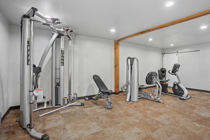 Modern fitness room featuring advanced exercise equipment including a multi-gym station, stationary bike, and bench press, all set in a spacious, well-lit environment.