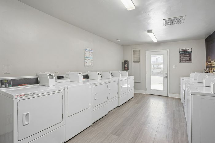 Bright and inviting laundry room with multiple washers and dryers, sleek flooring, and ample natural light.