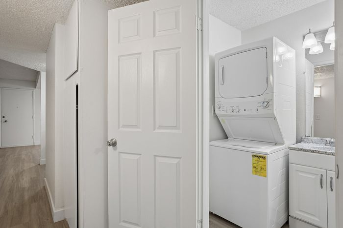 Convenient in-unit laundry setup with a sleek washer-dryer combo adjacent to a modern bathroom vanity.