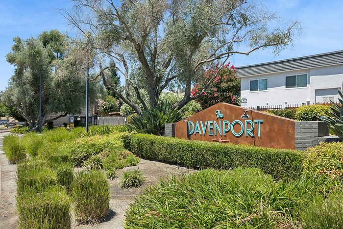 Inviting entrance to The Davenport, showcasing lush greenery and modern architecture, offering a serene community vibe.