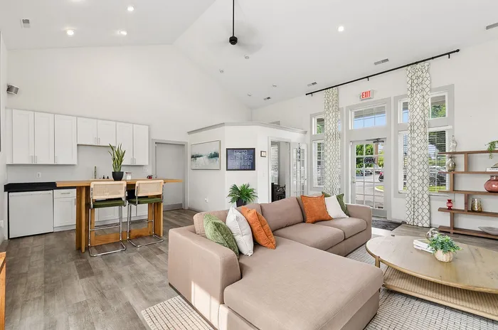 Chic living space featuring a modern open kitchen, stylish bar seating, and a cozy sectional sofa with vibrant cushions.