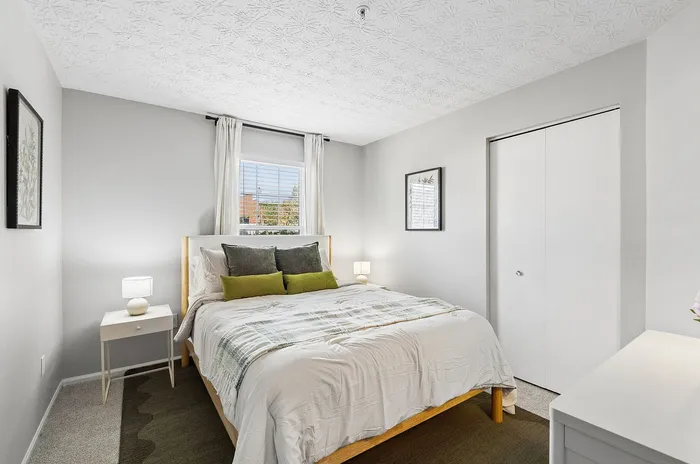 Bright and cozy bedroom with modern decor, a plush double bed, elegant side tables with lamps, and a picturesque window view.