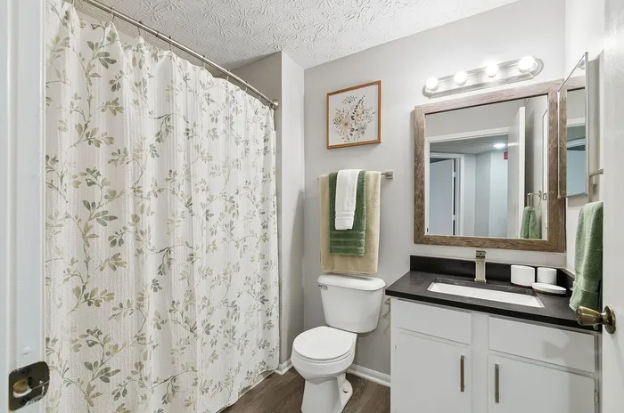 Elegant bathroom with stylish floral decor and modern lighting, featuring a pristine sink and inviting shower area.
