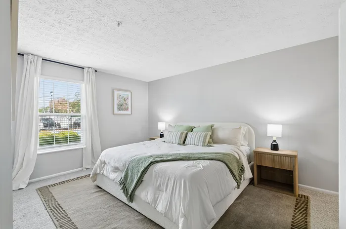 Bright and airy bedroom with elegant decor, featuring a large window, comfortable bed, and soft lighting for a cozy ambiance.
