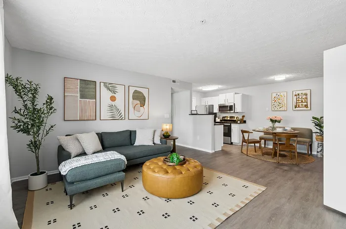 Elegant open-concept living space with modern decor, featuring a cozy sofa, stylish artwork, and a welcoming dining area connected to a contemporary kitchen.