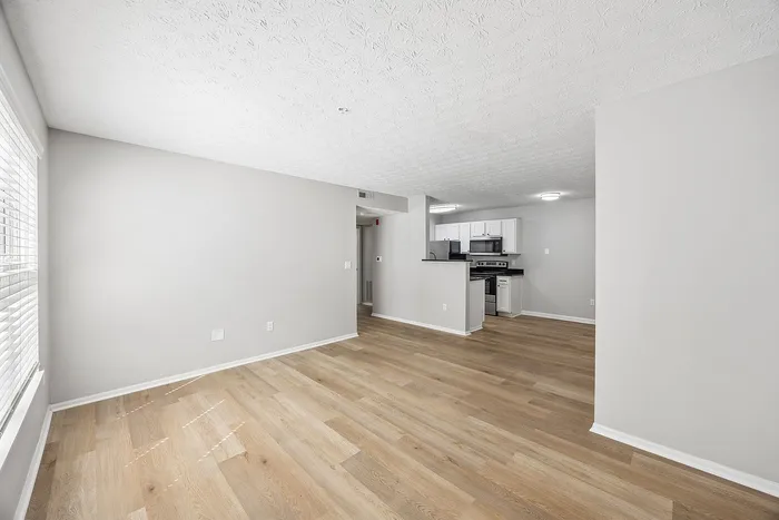 Bright and airy open living space with elegant hardwood floors, modern kitchen with sleek appliances, and a cozy sitting area.