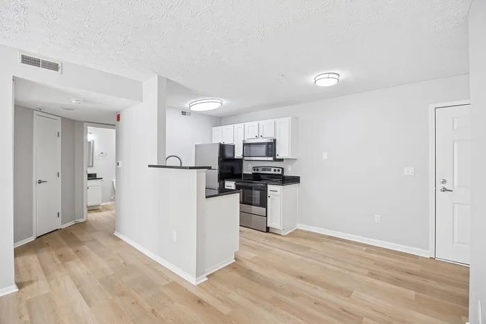 Modern kitchen with sleek stainless steel appliances, pristine white cabinetry, and elegant hardwood flooring in a bright, open layout.