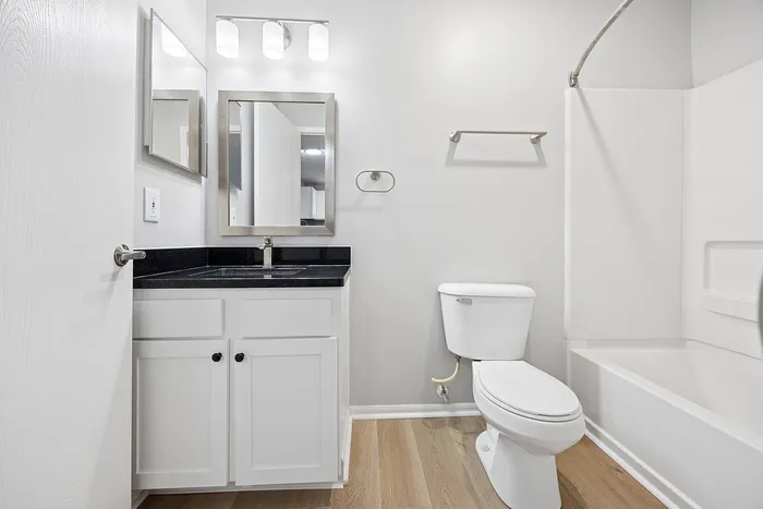 Modern bathroom with sleek black countertop, elegant white cabinets, and a pristine bathtub.