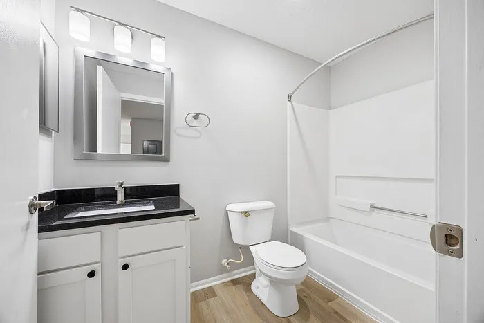 Modern bathroom with elegant lighting, sleek black countertop, and a pristine bathtub, offering a bright and inviting atmosphere.