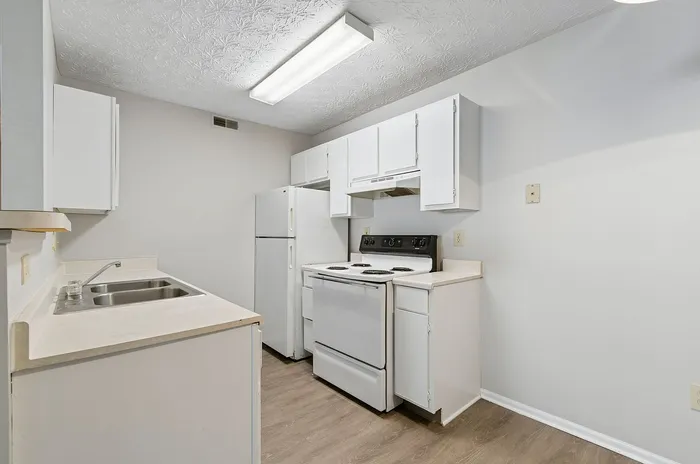 Bright and clean kitchen with modern white cabinetry, electric stove, and spacious countertops, ideal for culinary enthusiasts.