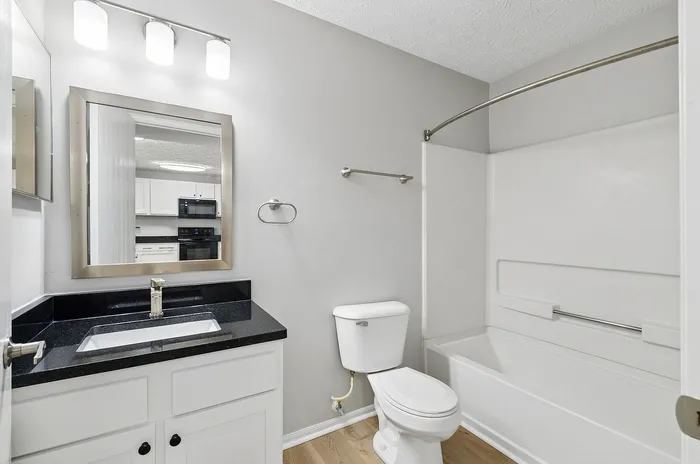 Modern bathroom with sleek vanity, polished countertop, and stylish mirror, featuring a clean and bright design.