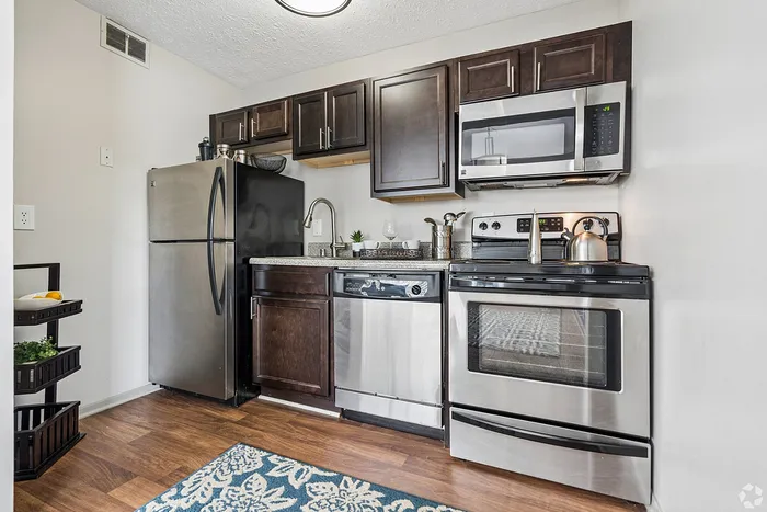 Modern kitchen with sleek stainless steel appliances, dark wood cabinets, and elegant countertops, offering a stylish and functional cooking space.