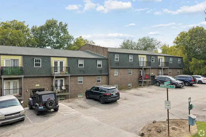 Charming apartment building with spacious balconies and ample parking set amidst lush greenery.