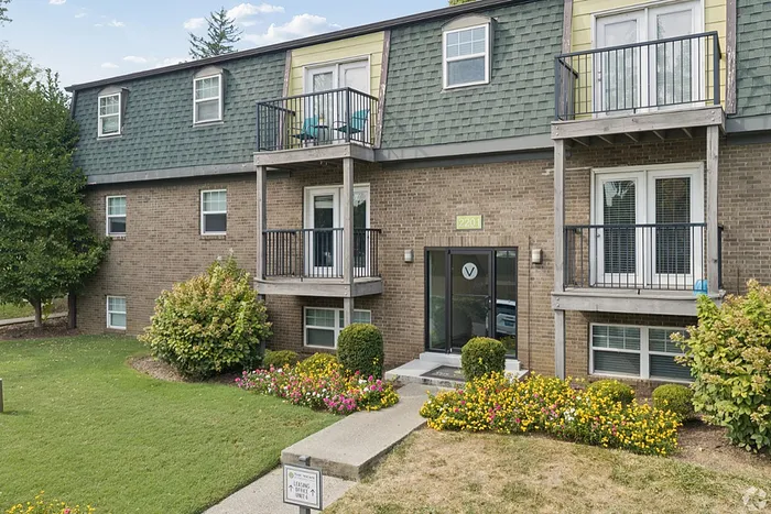 Charming apartment building with welcoming balconies, lush landscaping, and vibrant flowers, showcasing modern living in a serene environment.