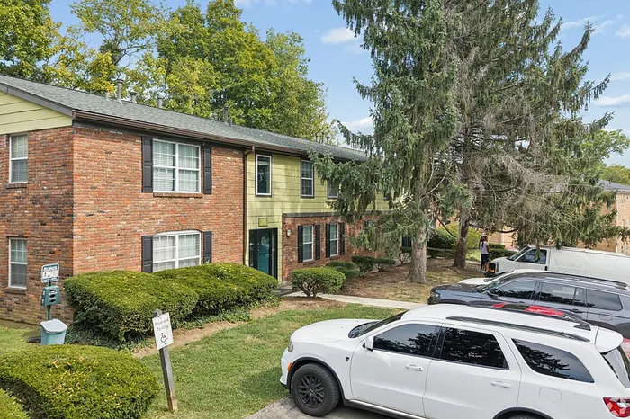 Charming two-story brick apartment surrounded by lush greenery and ample parking, perfect for serene living.