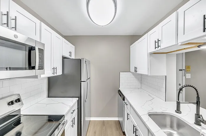 Contemporary kitchen with sleek white cabinetry, modern appliances, and elegant marble countertops.