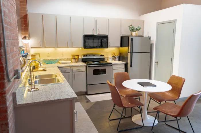 Contemporary kitchen with granite countertops, modern appliances, and a round dining table for four.
