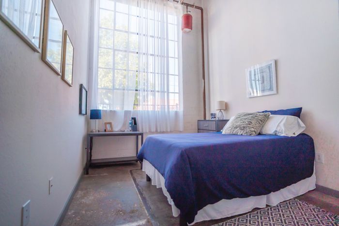 Bright and airy bedroom with large windows, stylish furnishings, and cozy decor.