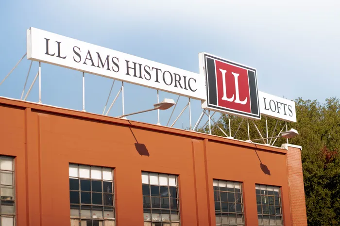 Exterior view of the LL Sams Historic Lofts, featuring a prominent sign atop a brick building with large windows.