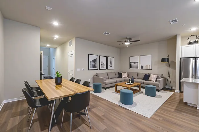 Contemporary living space showcasing an open-concept design with a stylish dining area, modern sectional sofa, chic artwork, and elegant kitchen with stainless steel appliances.