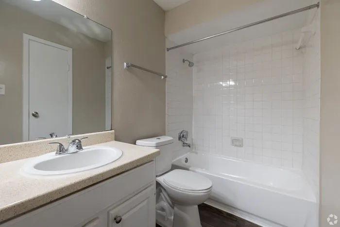 Contemporary bathroom with elegant white fixtures, spacious countertop, and pristine tiled bathtub, offering a sleek and inviting atmosphere.