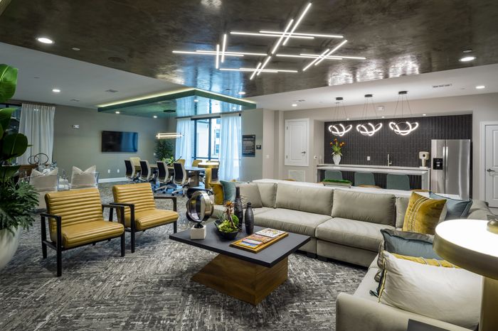 Modern and stylish apartment featuring a spacious living area with elegant ceiling lights, cozy seating, and a sleek kitchen with contemporary barstools and stainless steel appliances.