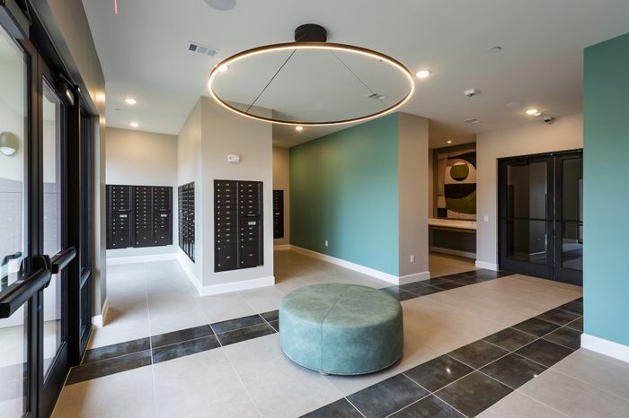 Modern apartment lobby with elegant design featuring sleek mailboxes, stylish circular seating, and contemporary lighting.