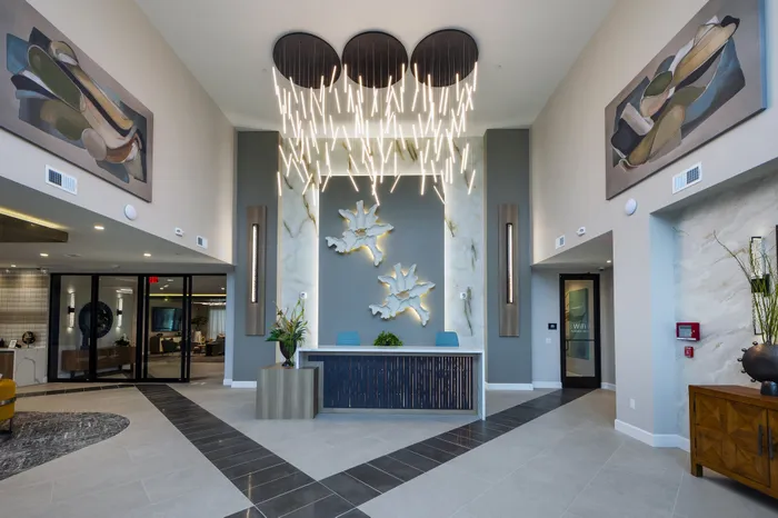 Elegant lobby with modern chandelier, abstract art, and sleek reception desk, creating a luxurious ambiance.