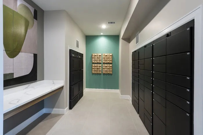 Modern apartment lobby with sleek lockers, artistic wall decor, and elegant marble countertop.