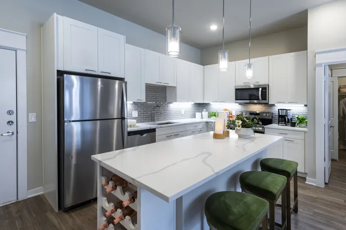 Contemporary kitchen with sleek white cabinets, stainless steel appliances, and a stylish island with green stools and built-in wine rack.