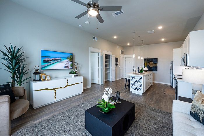 Modern open-concept living area featuring a sleek kitchen island, contemporary decor, and inviting living space with large TV display.