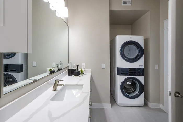 Modern bathroom with sleek vanity and integrated washer-dryer, perfect for stylish apartment living.