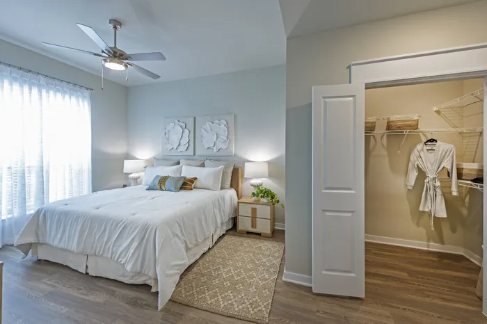 Inviting bedroom with a plush bed, elegant wall art, and spacious walk-in closet, featuring neutral tones and abundant natural light.