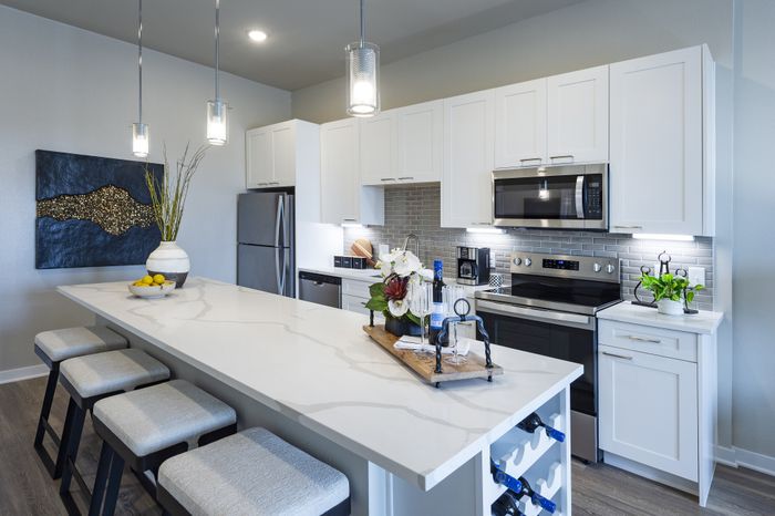 Modern kitchen with elegant white cabinetry, stainless steel appliances, and a chic island with contemporary bar stools, ideal for stylish entertaining.