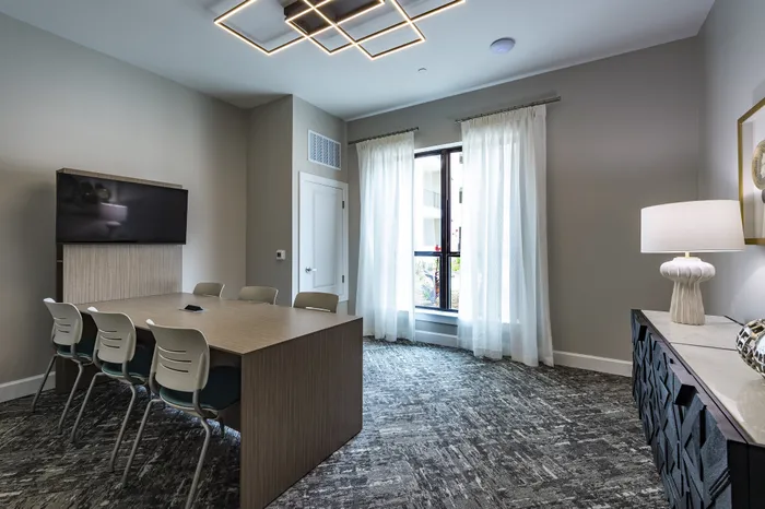 Modern office space with artistic wall decor, featuring a sleek wooden table, contemporary chairs, and a stylish textured cabinet with elegant lighting.