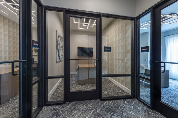 Modern office space with artistic wall decor, featuring a sleek wooden table, contemporary chairs, and a stylish textured cabinet with elegant lighting.
