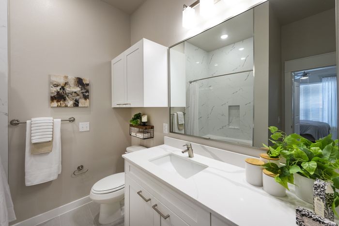 Elegant modern bathroom with sleek white cabinetry, stylish marble countertop, and large mirror reflecting natural light.
