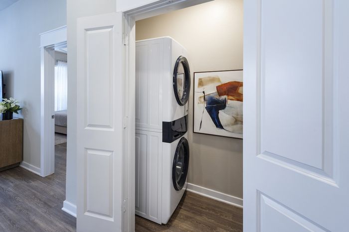 Contemporary apartment with a convenient stacked washer and dryer in a chic laundry nook, accented with modern art and sleek hardwood flooring.