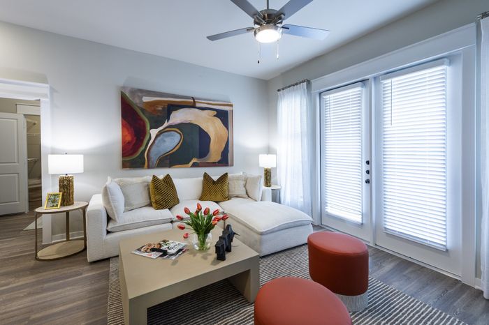 Contemporary living room featuring a cozy white sofa, abstract artwork, vibrant tulips on a sleek coffee table, and elegant French doors.