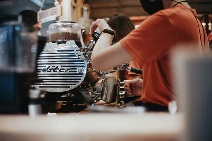Barista expertly prepares coffee with a sleek espresso machine in a bustling café.