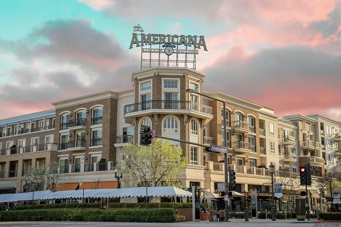 Charming urban apartment complex with elegant balconies and lush landscaping under a vibrant pink and blue sunset sky.