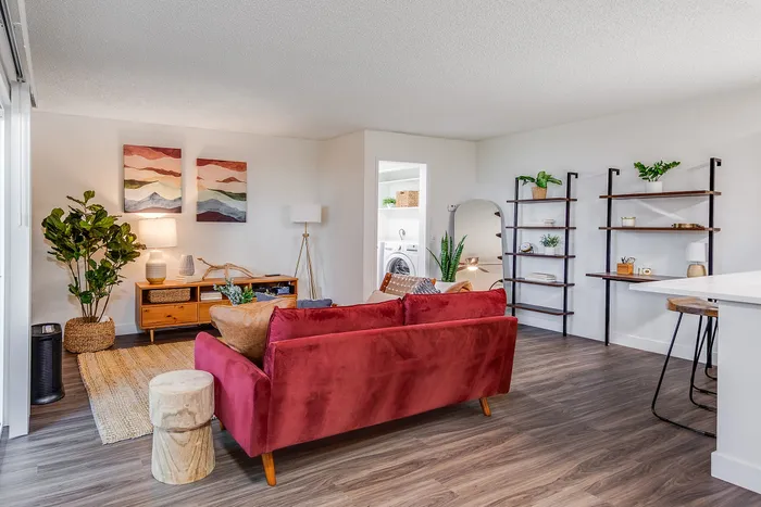 Modern living room with a chic red sofa, elegant wood floors, and tasteful decor; perfect for stylish urban living.