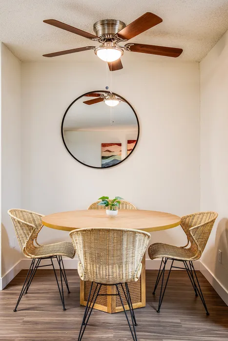 Charming dining area with a natural wood table and wicker chairs, featuring a stylish ceiling fan and modern decor.