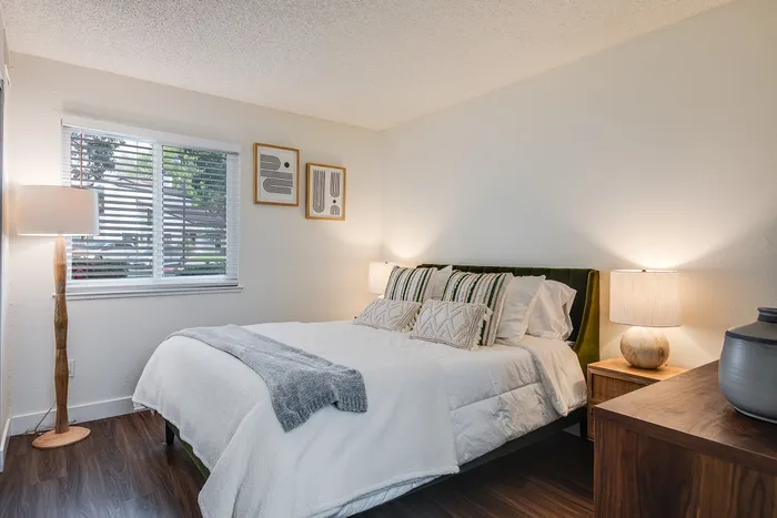 Inviting bedroom with modern decor, featuring a cozy bed adorned with stylish cushions, elegant nightstands, and warm ambient lighting.