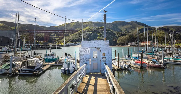Inviting marina scene with vibrant sailboats and a scenic bridge backdrop, perfect for leisurely waterfront living.