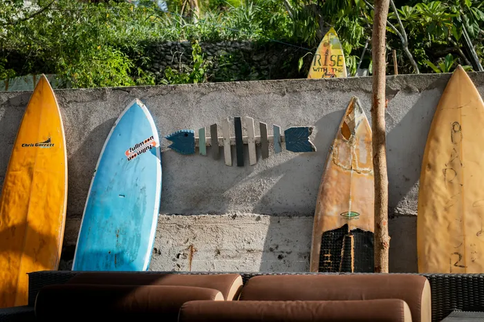 Vibrant backyard setting with colorful surfboards against a rustic wall, creating a relaxed and inviting coastal vibe.
