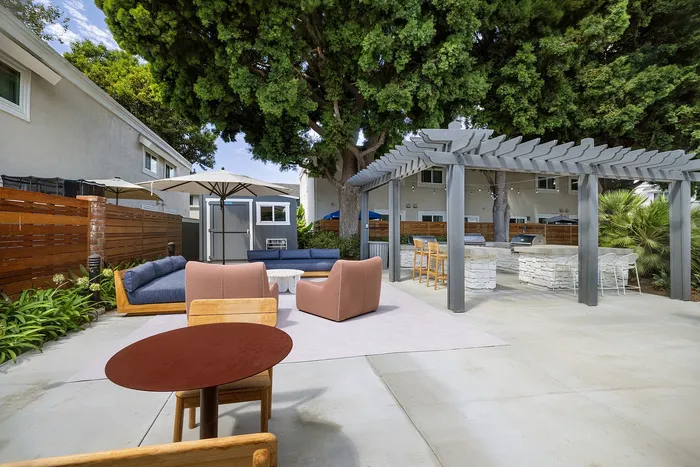 Chic outdoor patio with modern seating, shaded pergola, and lush greenery, ideal for relaxation and entertaining.