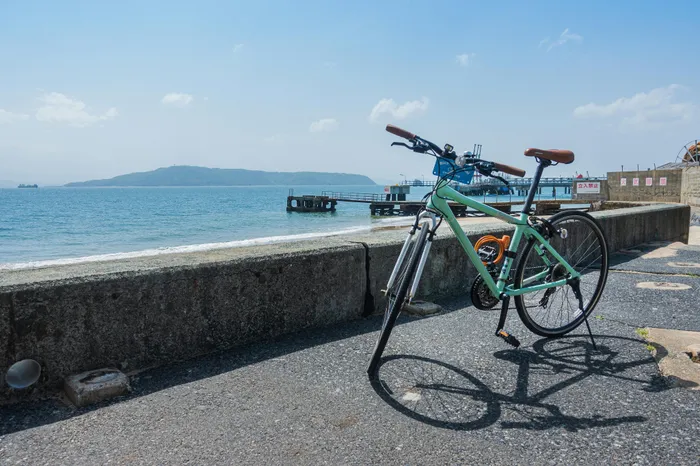 Inviting coastal scene with a green bicycle parked by a seaside pier, offering picturesque ocean views and a distant island silhouette.